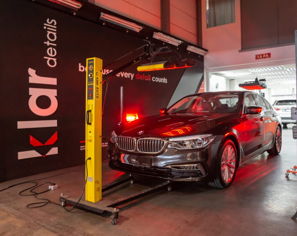 Black BMW under infrared curing lamps