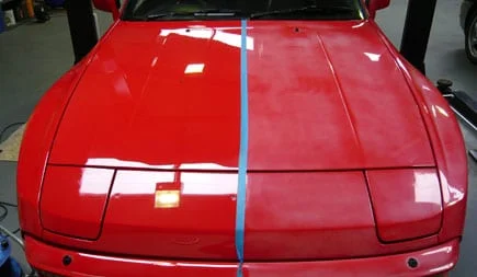 Red car hood showing glossy paint correction results beside dull faded paint