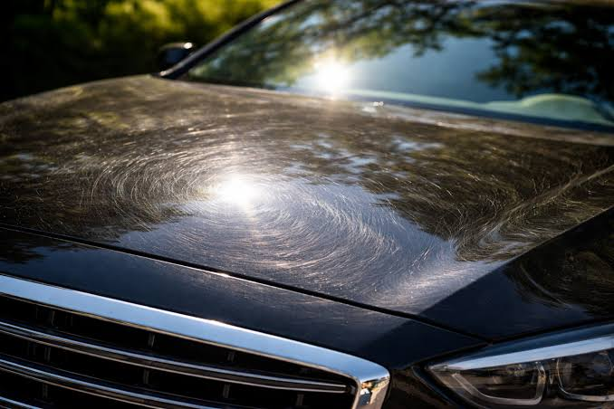 Swirl marks and scratches on a black car hood